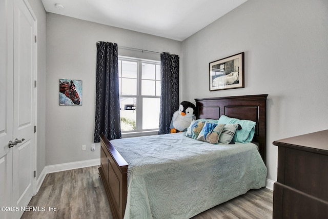 bedroom featuring multiple windows, baseboards, and wood finished floors