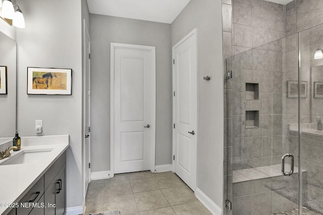 bathroom featuring baseboards, vanity, a shower stall, and tile patterned flooring