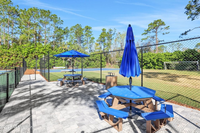 view of patio / terrace with a tennis court and fence