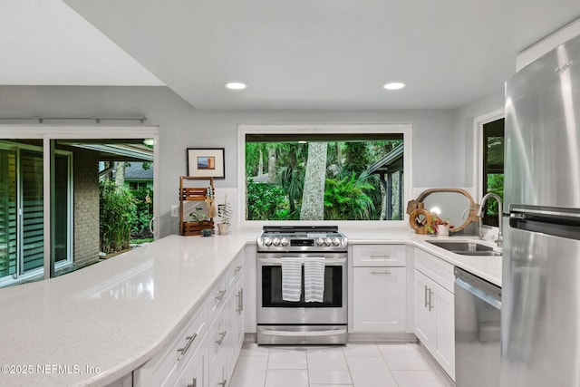 kitchen featuring appliances with stainless steel finishes, a sink, light tile patterned floors, white cabinets, and recessed lighting