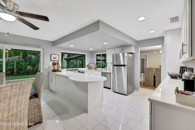 kitchen with appliances with stainless steel finishes, a peninsula, white cabinets, ceiling fan, and recessed lighting