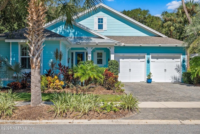 view of front facade featuring decorative driveway, roof with shingles, and an attached garage