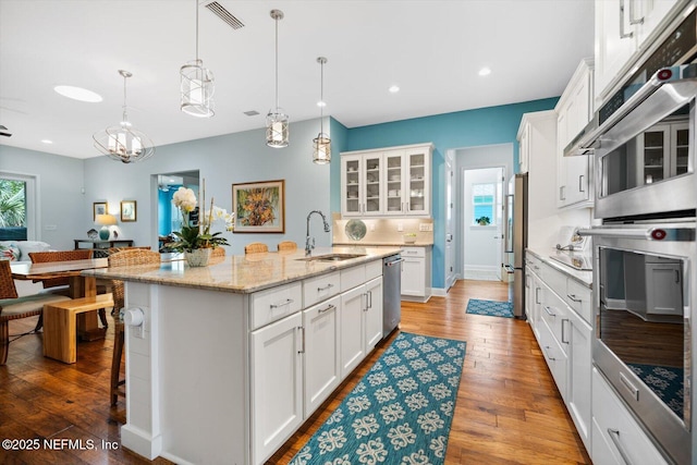 kitchen featuring visible vents, white cabinets, appliances with stainless steel finishes, hardwood / wood-style floors, and a sink