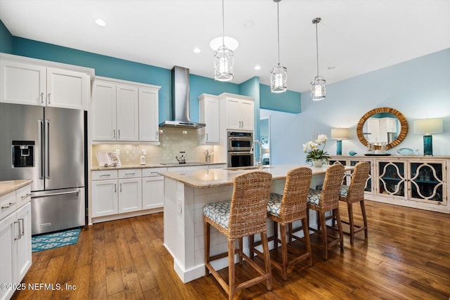 kitchen with stainless steel appliances, wall chimney range hood, dark wood-type flooring, and decorative backsplash