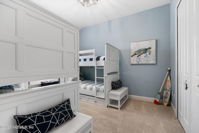 bedroom with baseboards, a closet, and light colored carpet