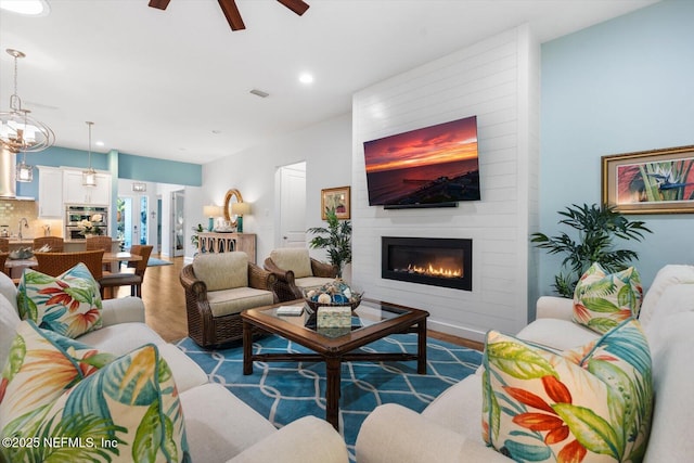 living area featuring a large fireplace, visible vents, ceiling fan, wood finished floors, and recessed lighting