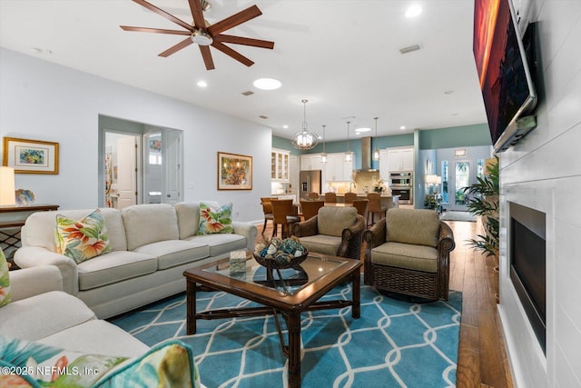 living area featuring dark wood-style floors, a fireplace, visible vents, and recessed lighting