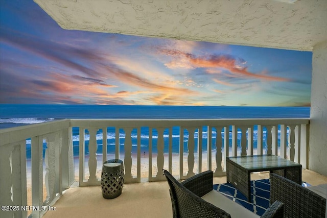 balcony featuring a water view and a view of the beach