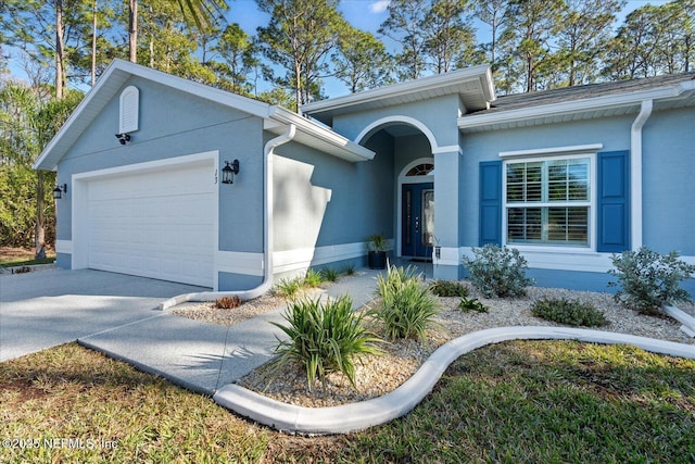 ranch-style home with a garage, concrete driveway, and stucco siding