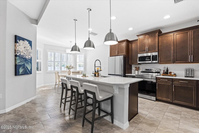 kitchen featuring visible vents, a kitchen breakfast bar, light countertops, stainless steel appliances, and a sink