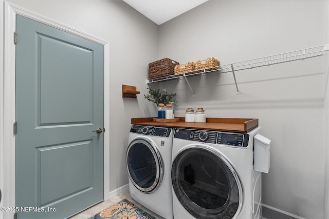 laundry area featuring laundry area, light tile patterned floors, baseboards, and washer and clothes dryer