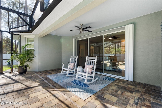 view of patio / terrace with a ceiling fan and glass enclosure