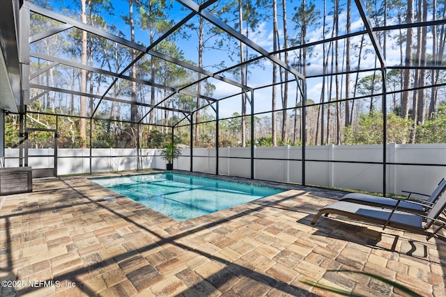 view of pool with a patio, fence, and glass enclosure