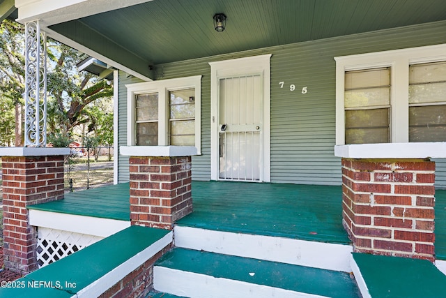 entrance to property featuring brick siding and a porch