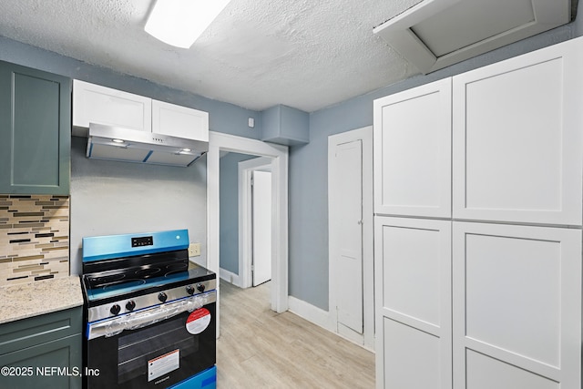 kitchen featuring under cabinet range hood, a textured ceiling, stainless steel electric range, light wood finished floors, and decorative backsplash