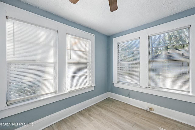 spare room featuring baseboards, a textured ceiling, ceiling fan, and light wood finished floors