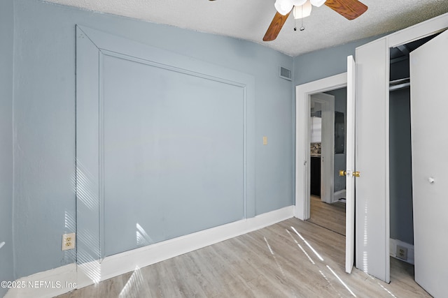 unfurnished bedroom with visible vents, baseboards, light wood-style flooring, a textured ceiling, and a ceiling fan