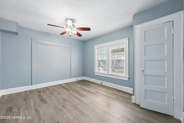 empty room featuring ceiling fan, baseboards, a textured ceiling, and wood finished floors