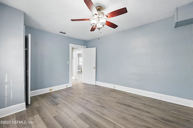 unfurnished bedroom with visible vents, ceiling fan, baseboards, wood finished floors, and a textured ceiling