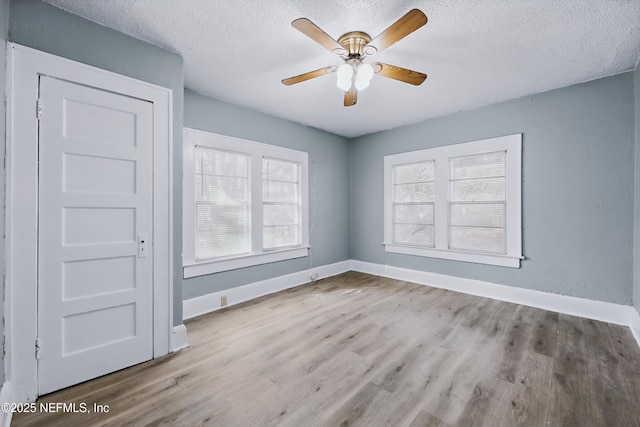 spare room with a textured ceiling, a ceiling fan, baseboards, and wood finished floors