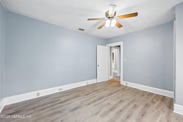 spare room with a textured ceiling, baseboards, visible vents, and light wood-type flooring