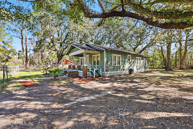 view of side of home featuring covered porch and fence