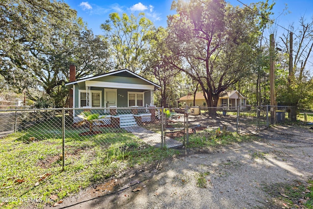 view of front of home featuring a fenced front yard, a porch, a chimney, and a gate