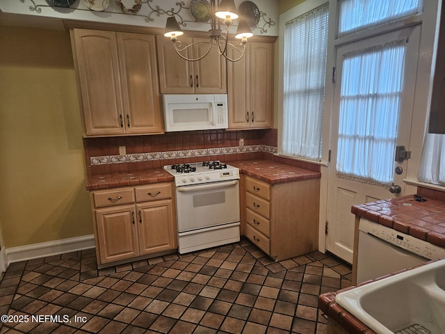 kitchen with tasteful backsplash, a notable chandelier, tile countertops, and white appliances