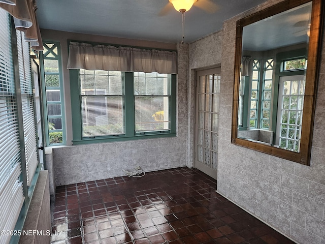 unfurnished sunroom with a ceiling fan