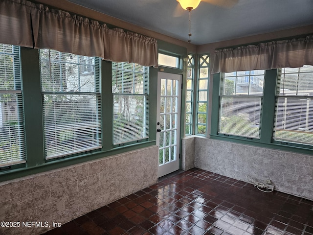 unfurnished sunroom featuring ceiling fan