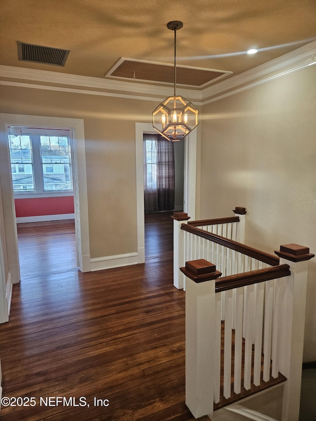 staircase featuring wood finished floors, visible vents, attic access, ornamental molding, and a wealth of natural light