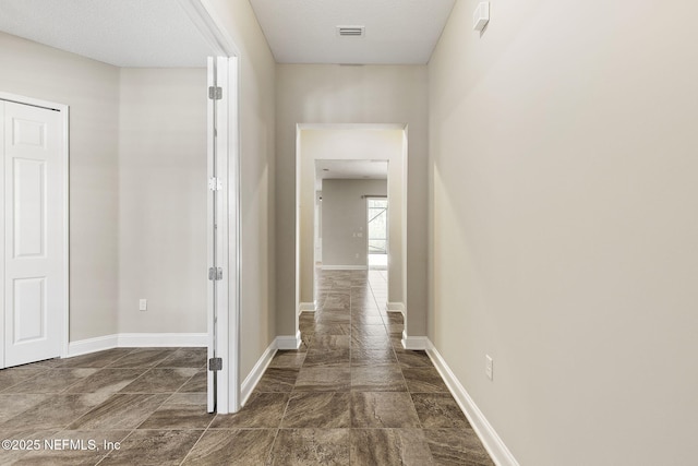 hall with baseboards and visible vents