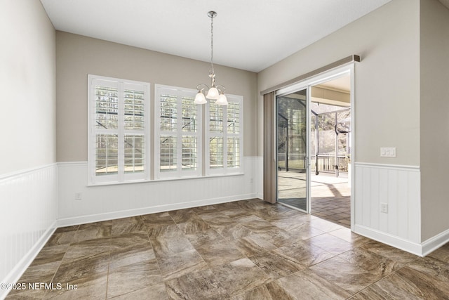 unfurnished dining area with a wainscoted wall and an inviting chandelier