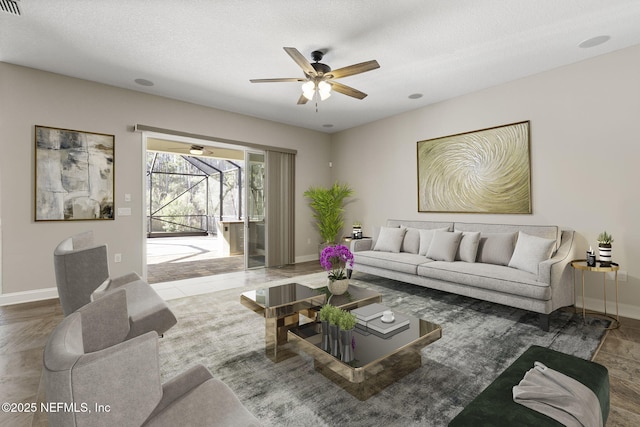 living area featuring a textured ceiling, baseboards, ceiling fan, and a sunroom