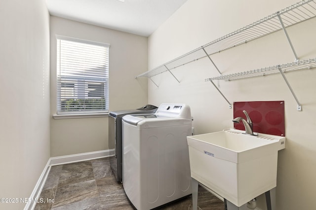 laundry area with a sink, laundry area, baseboards, and washing machine and clothes dryer