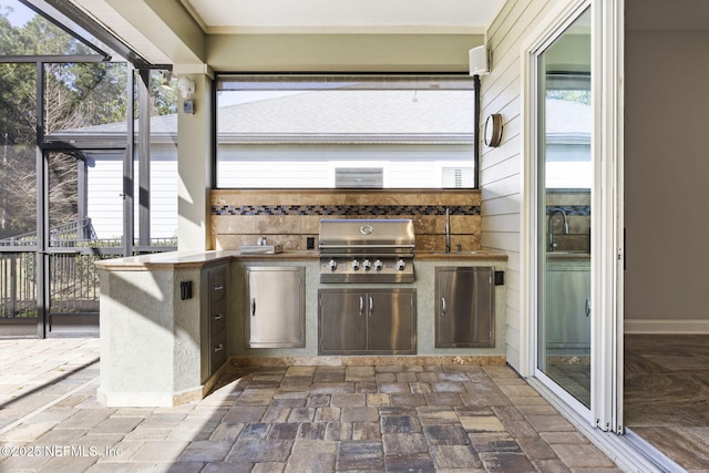 view of patio with glass enclosure, area for grilling, a sink, and an outdoor kitchen