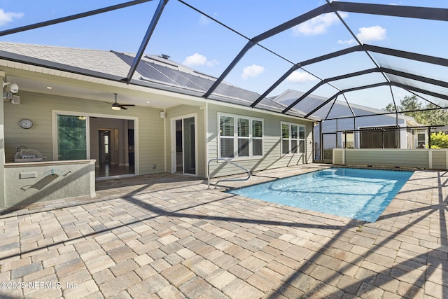 pool featuring ceiling fan, glass enclosure, an outdoor kitchen, and a patio area