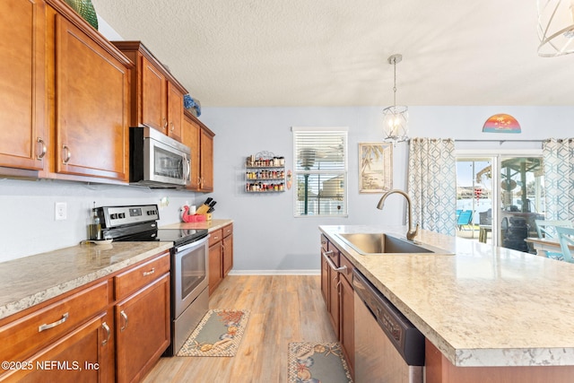 kitchen with appliances with stainless steel finishes, a wealth of natural light, light countertops, and a sink