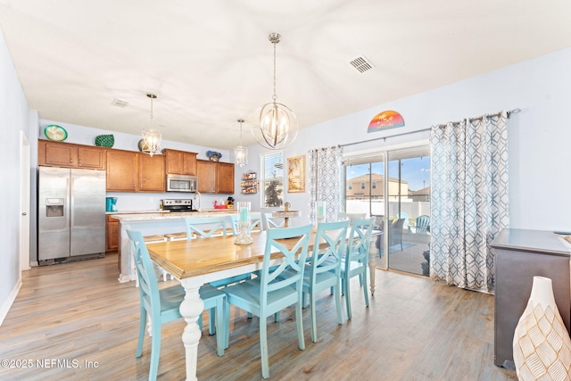 dining room featuring visible vents, a notable chandelier, and light wood-style flooring