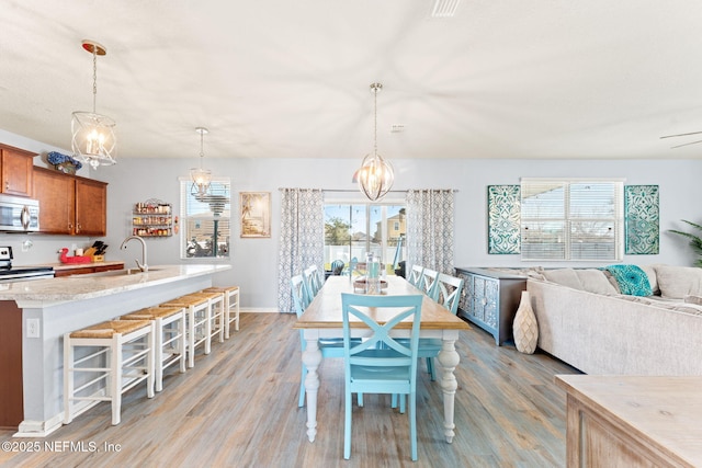 dining room featuring baseboards, light wood finished floors, and an inviting chandelier