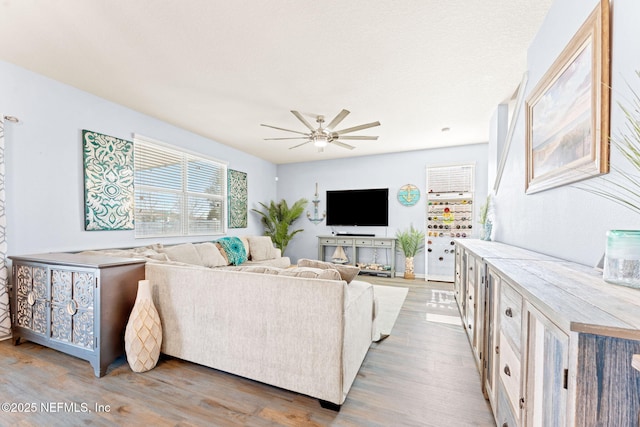 living area with a ceiling fan and wood finished floors