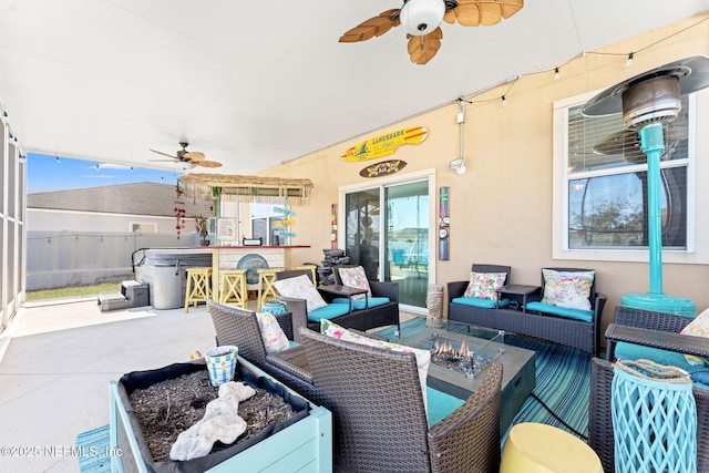 view of patio / terrace with ceiling fan, a hot tub, an outdoor living space with a fire pit, and fence