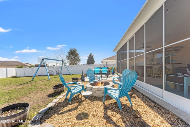 view of yard featuring a sunroom, a fenced backyard, a patio, and a fire pit