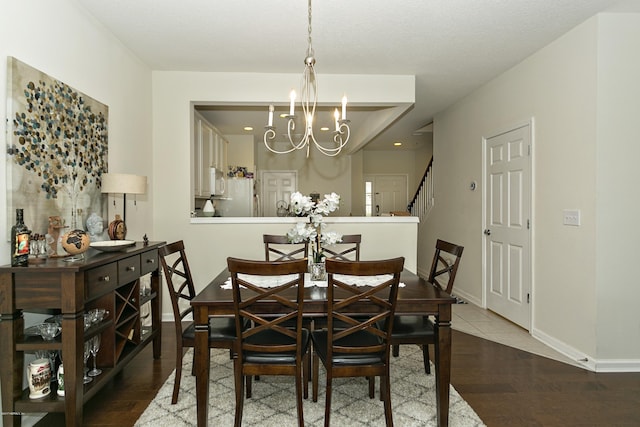 dining area with stairs, an inviting chandelier, wood finished floors, and baseboards