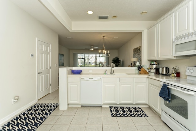 kitchen featuring a sink, white appliances, a peninsula, light tile patterned flooring, and light countertops