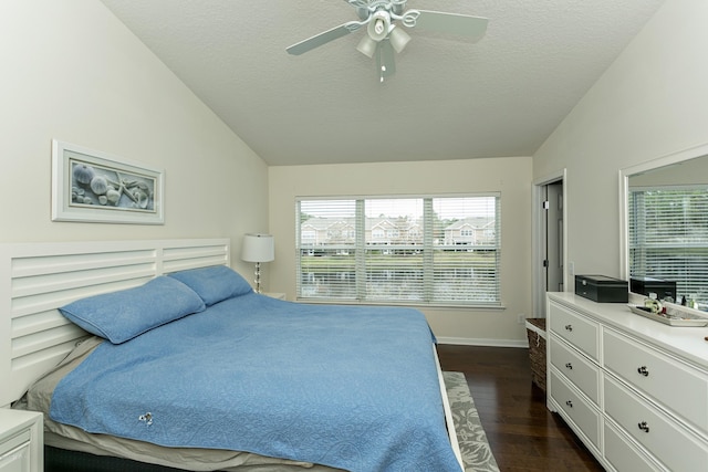 bedroom with a textured ceiling, dark wood-type flooring, ceiling fan, and vaulted ceiling