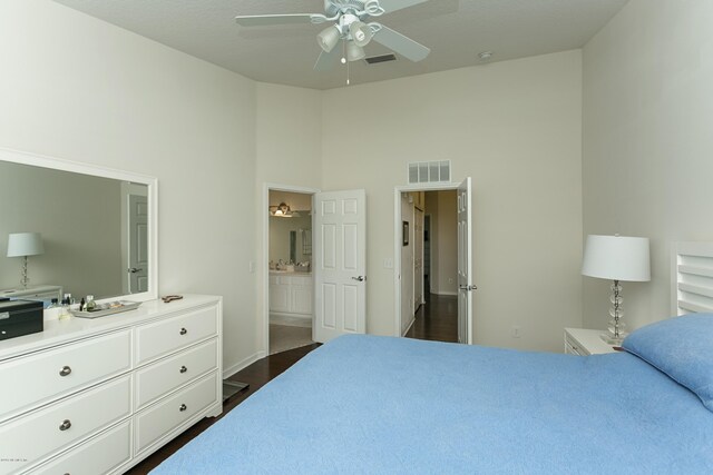 bedroom featuring visible vents, dark wood-type flooring, ensuite bathroom, a ceiling fan, and a high ceiling