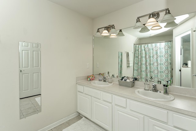 full bathroom featuring tile patterned flooring, double vanity, baseboards, and a sink