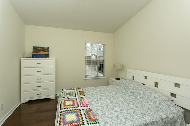 bedroom with baseboards, dark wood-type flooring, and lofted ceiling