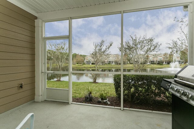 unfurnished sunroom featuring a residential view and a water view